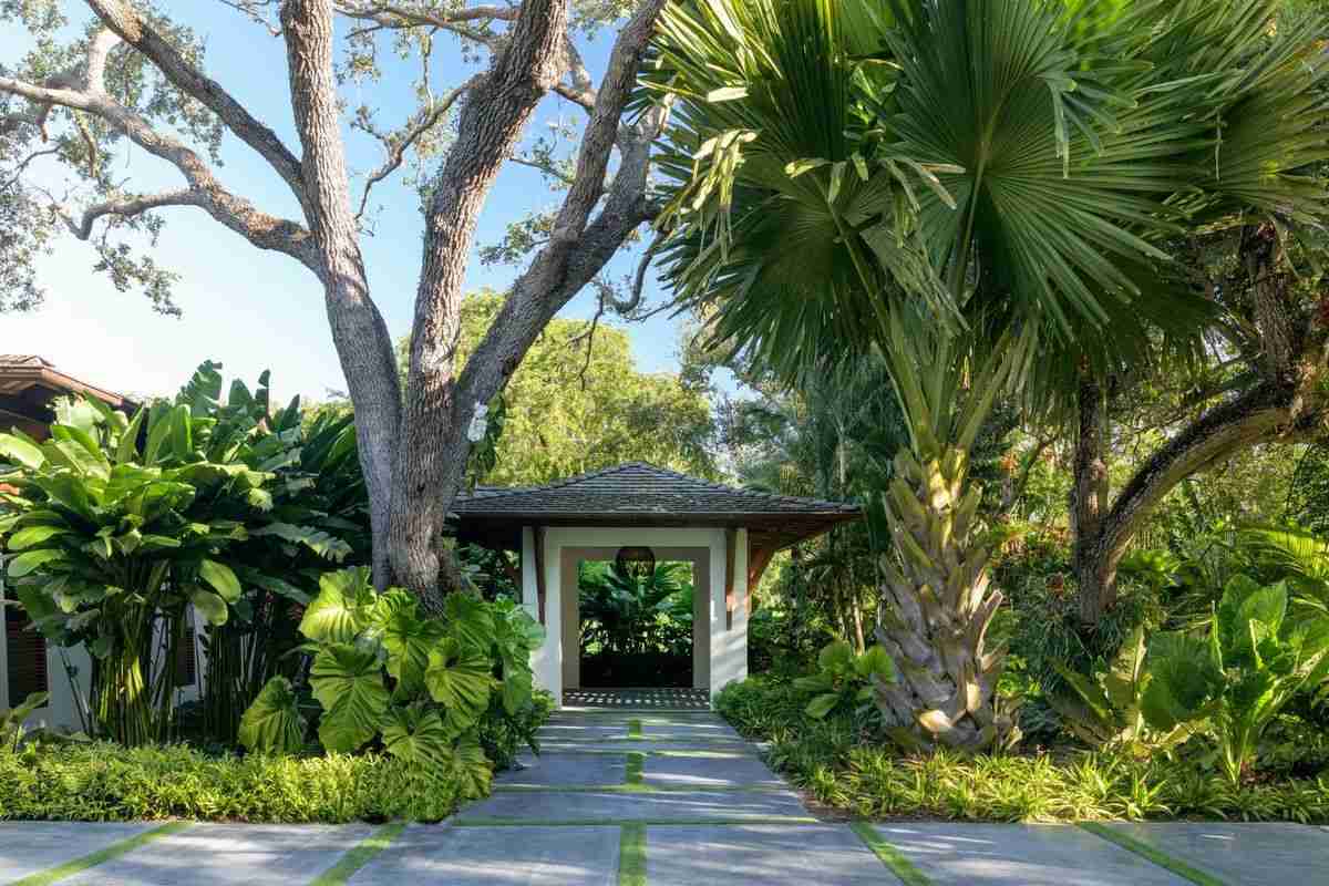 Cây Nhiệt Đới – Linh Hồn Xanh Của Cảnh Quan Nhiệt Đới Biệt Thự Hiện Đại 5 Lối vào xanh mát với cây nhiệt đới bao quanh kiến trúc mái truyền thống