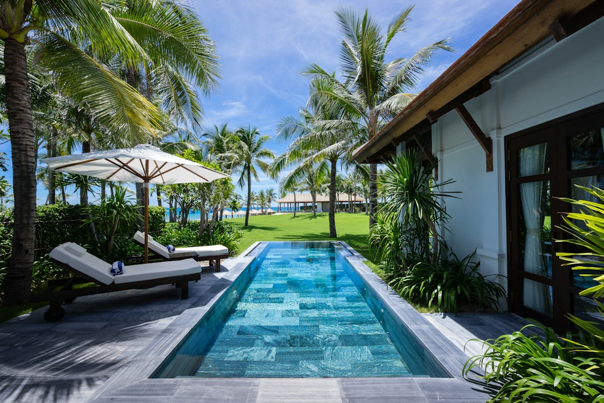 Cây Trồng Quanh Hồ Bơi: 9 Loại Đẹp, Ít Rụng Lá 1 Cây trồng quanh hồ bơi với hàng cọ và thảm cỏ bên biệt thự