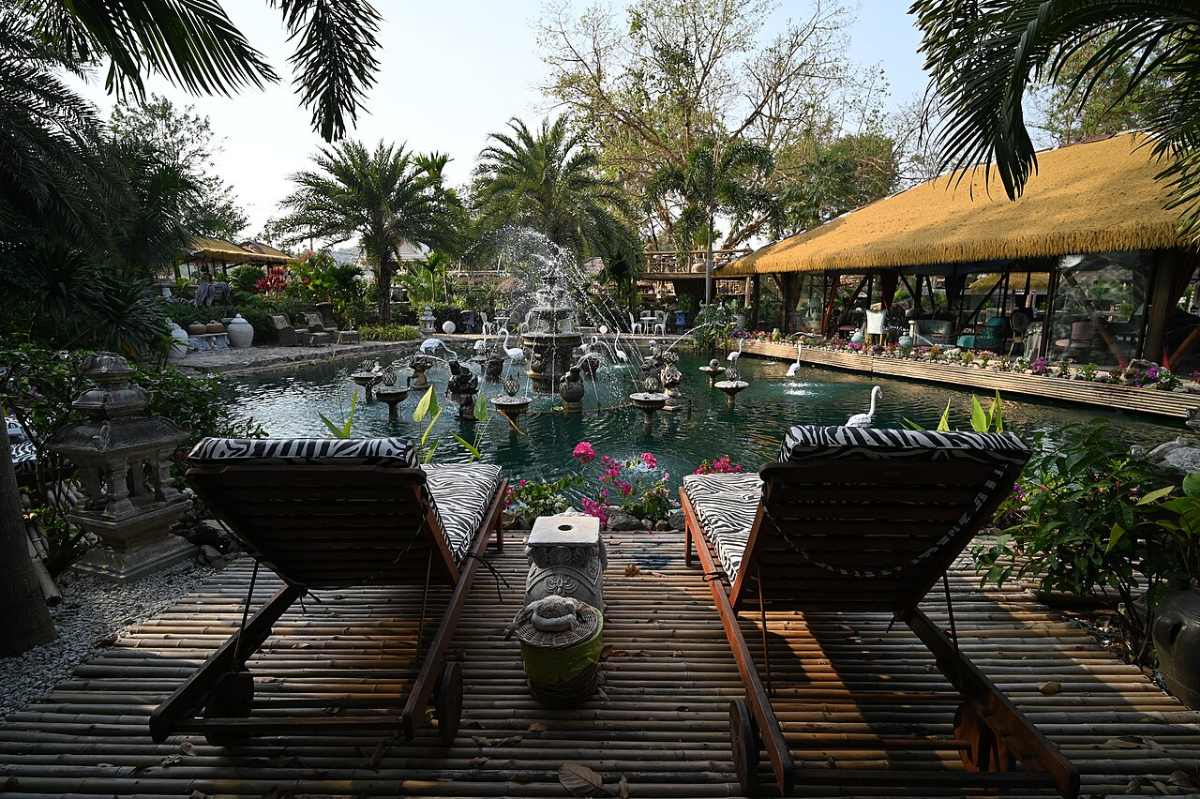 Thiết Kế Sân Vườn Villa Nghỉ Dưỡng: 8 Nguyên Tắc Đẹp Như Resort 2026 7 Góc thư giãn với ghế tắm nắng trên sàn gỗ bên hồ nước villa