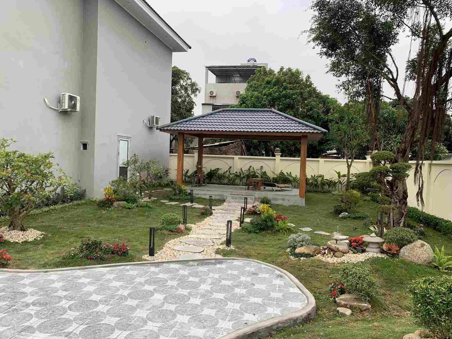 Thiết Kế Cảnh Quan Á Đông: Tạo Không Gian Sống Biết Thở, Biết Nghe 2 Cảnh quan Á Đông trong sân vườn biệt thự với chòi nghỉ truyền thống, lối đi lát đá và tiểu cảnh đá cây phong thủy.