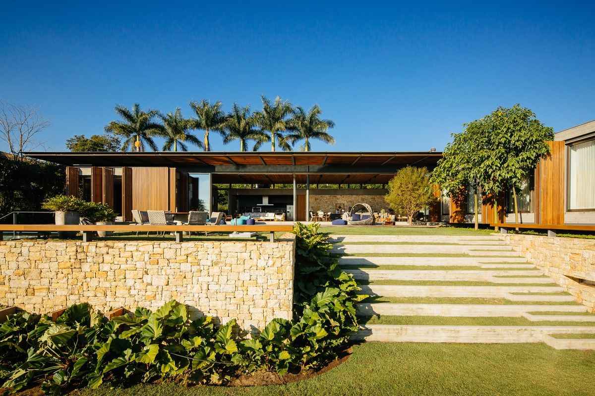 Sân vườn kiểu resort với kiến trúc mở và hàng cọ nhiệt đới phía sau