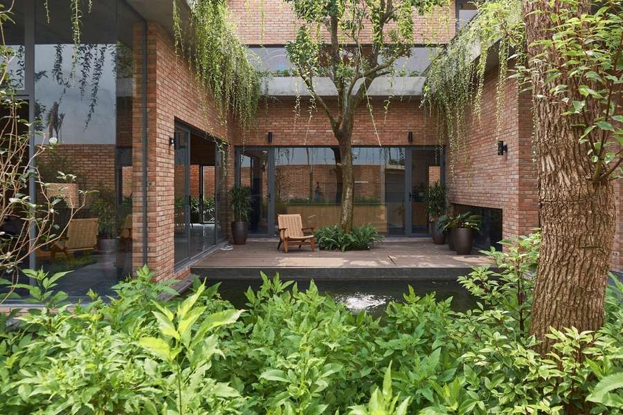 Không gian sân vườn biệt thự hiện đại sử dụng vật liệu xanh như gạch thô, gỗ mộc và cây xanh tự nhiên.